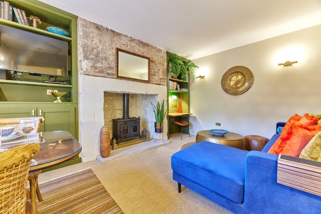 a living room with a blue couch and a fireplace at Cinnabar: Luxury, Couple's Nook in Historic Walls. in Berwick-Upon-Tweed