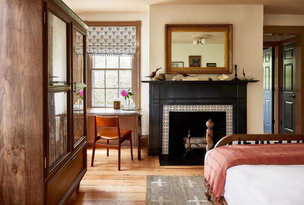 1 dormitorio con chimenea, espejo y cama en Blue Iris by Life House, en Nantucket