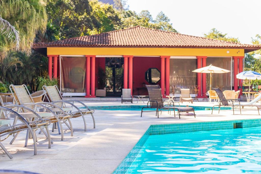 um resort com uma piscina com cadeiras e guarda-sóis em Bomtempo II Chales by Castelo Itaipava em Itaipava