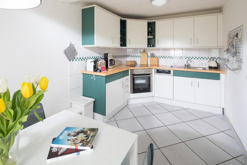 uma cozinha com armários brancos e verdes e uma mesa em Lüttje Schmiede em Norderney