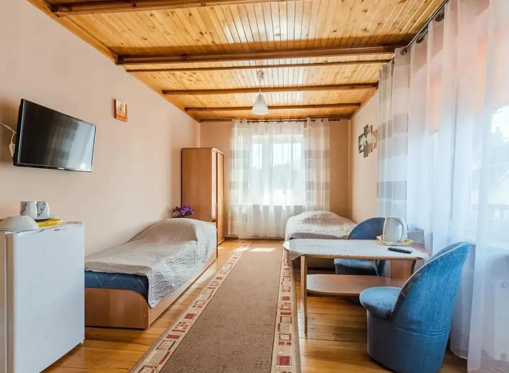 a room with two beds and a table and chairs at Pokoje Wilkasy in Wilkasy