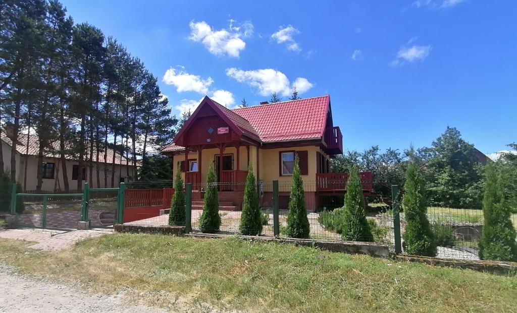 a small yellow house with a red roof at Domek letniskowy OSP in Ogonki