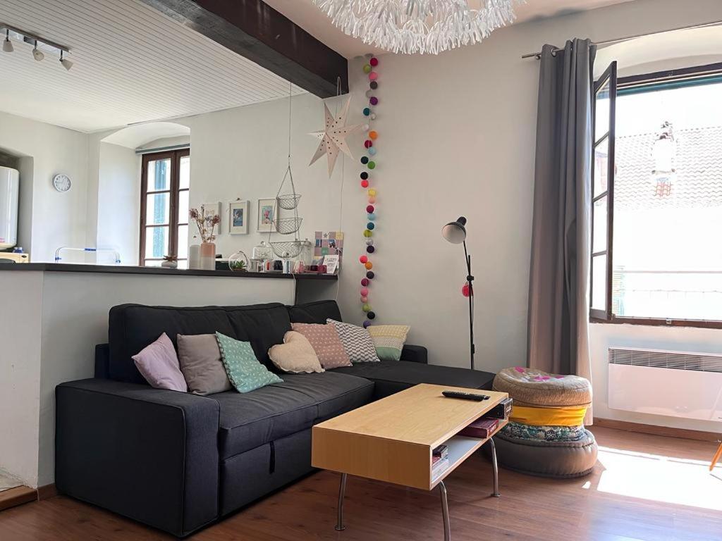 a living room with a black couch and a table at Joli appartement F2 centre ville de Corte in Corte