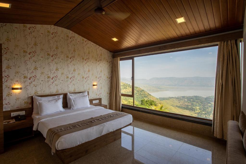a bedroom with a bed and a large window at Miraya Hotel in Panchgani