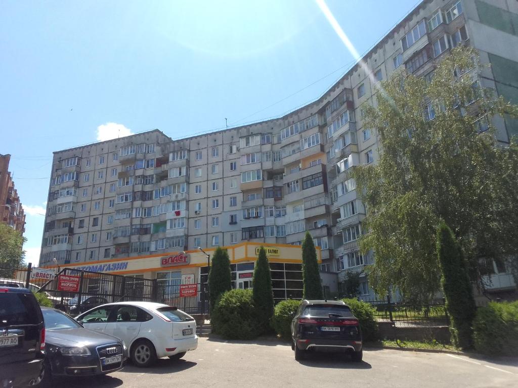 a large building with cars parked in a parking lot at Soborna Street 259, three-room apartment in Rivne
