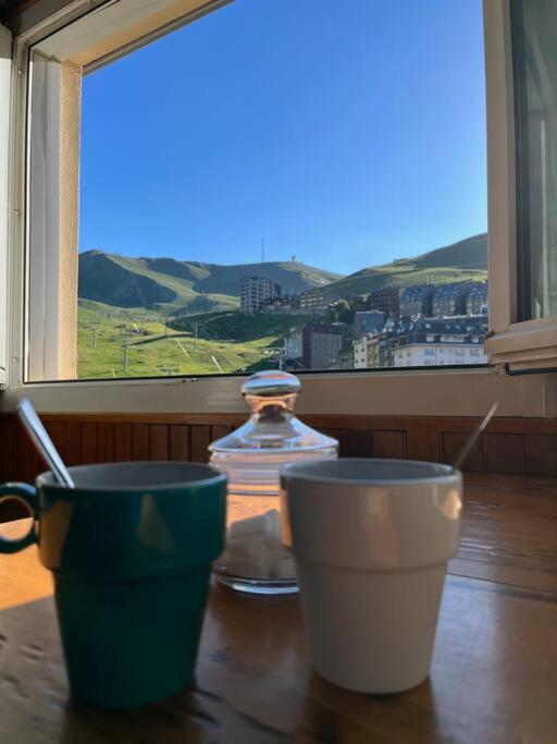 duas xícaras sentadas numa mesa em frente a uma janela em Envalira Vacances - Etoile duplex ideal familia con vista a pistas em Pas de la Casa