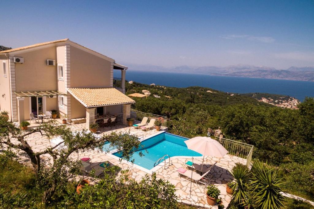 a house with a swimming pool next to the ocean at Villa Maria Kassiopi by Villa Plus in Kelliá