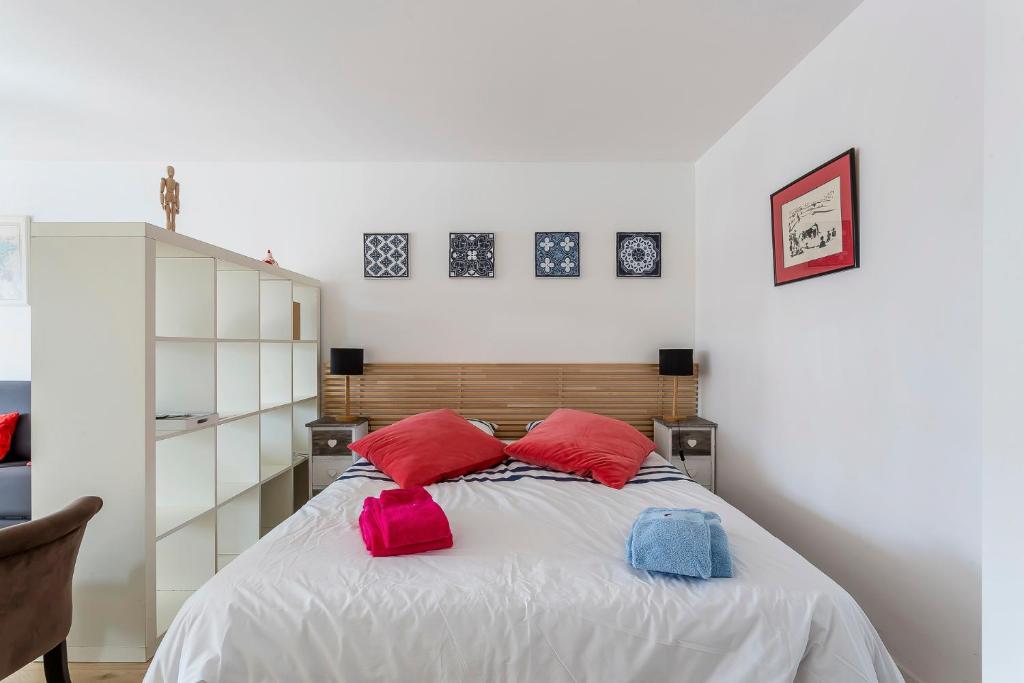 - une chambre dotée d'un lit avec des oreillers rouges et roses dans l'établissement Studio du Maréchal, à Sainte-Foy-lès-Lyon