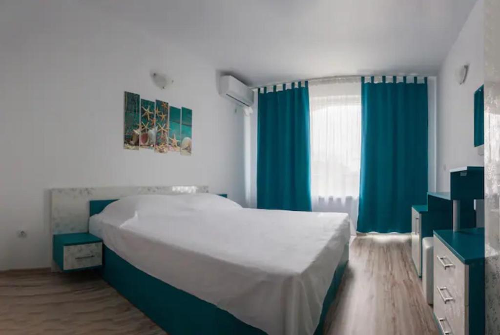 een slaapkamer met een groot bed en blauwe gordijnen bij Къща за гости - Пролет in Lozenets