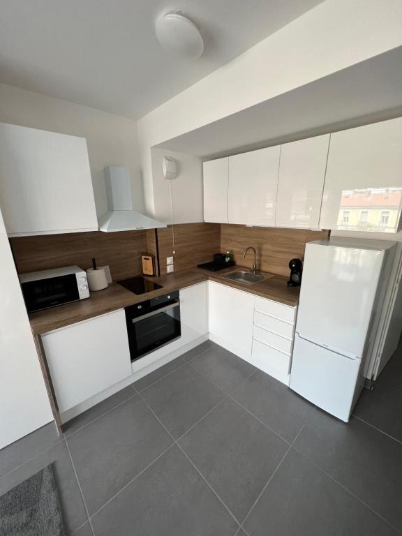uma pequena cozinha com armários brancos e um lavatório em Appartement tout équipé centre ville Menton em Menton