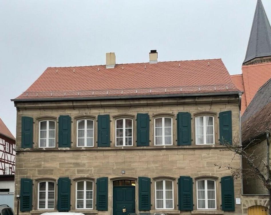 海德克的住宿－Ferienhaus Heideck，一座带绿色百叶窗和红色屋顶的建筑