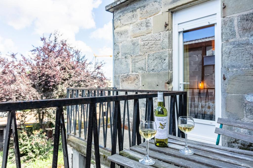 two glasses of white wine sitting on a wooden bench at Cosy Apparts Brive in Brive-la-Gaillarde