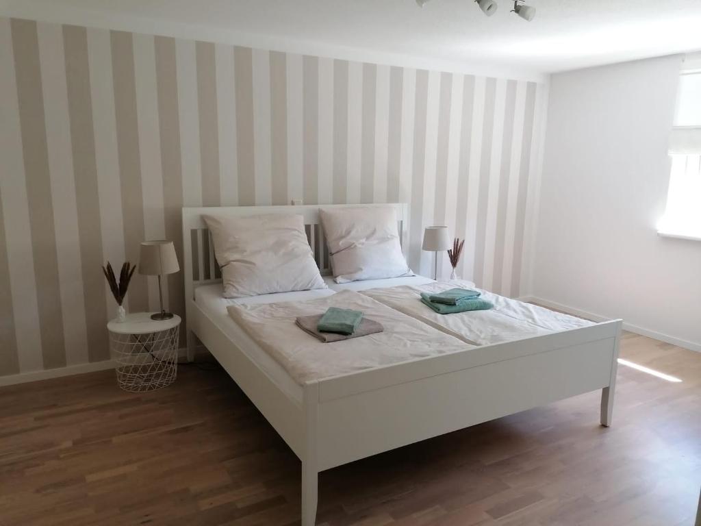 a white bed in a room with striped walls at Ferienwohnung Auengrund in Grub am Forst