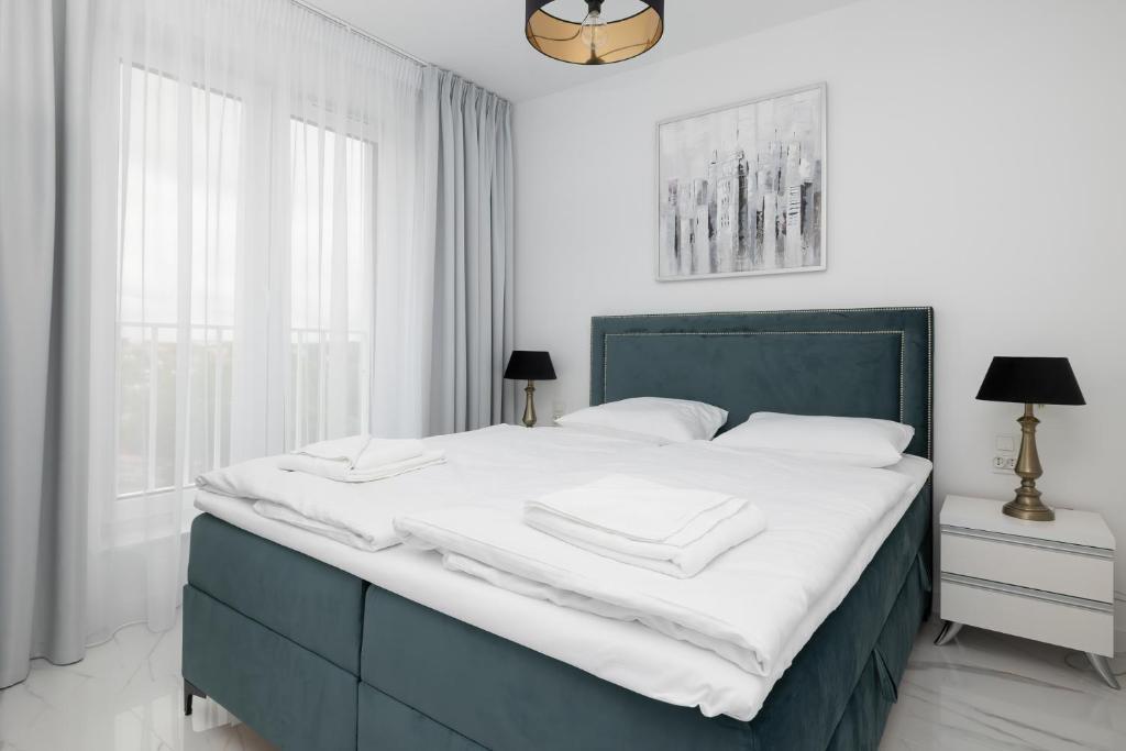 sypialnia z dużym łóżkiem z białymi prześcieradłami w obiekcie Apartament DIAMOND w Kołobrzegu