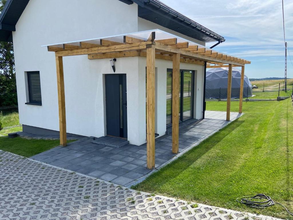 una pequeña casa blanca con pérgola de madera en Ojców Domek DELUX ,Apartamenty z Jacuzzi en Wola Kalinowska