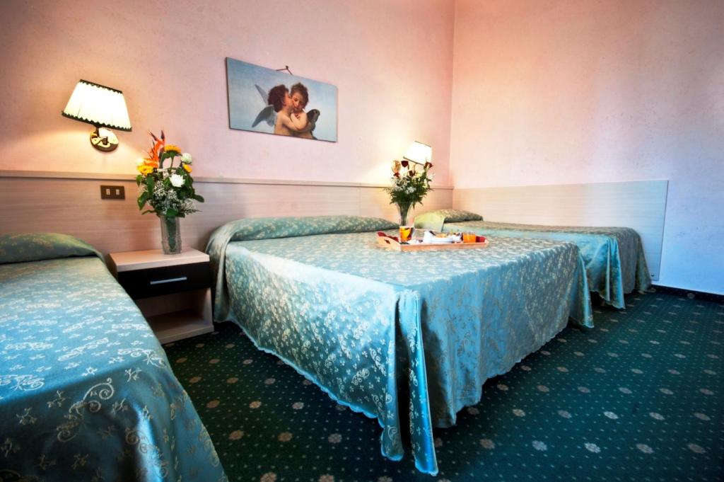 a hotel room with two beds and a table with flowers at Hotel Priscilla in Rome
