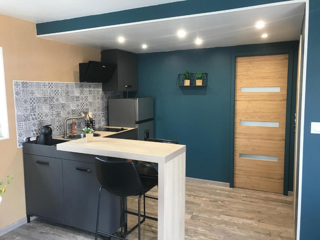 eine Küche mit einer weißen Theke und einer blauen Wand in der Unterkunft Appartement neuf avec jardin privatif in Périgueux