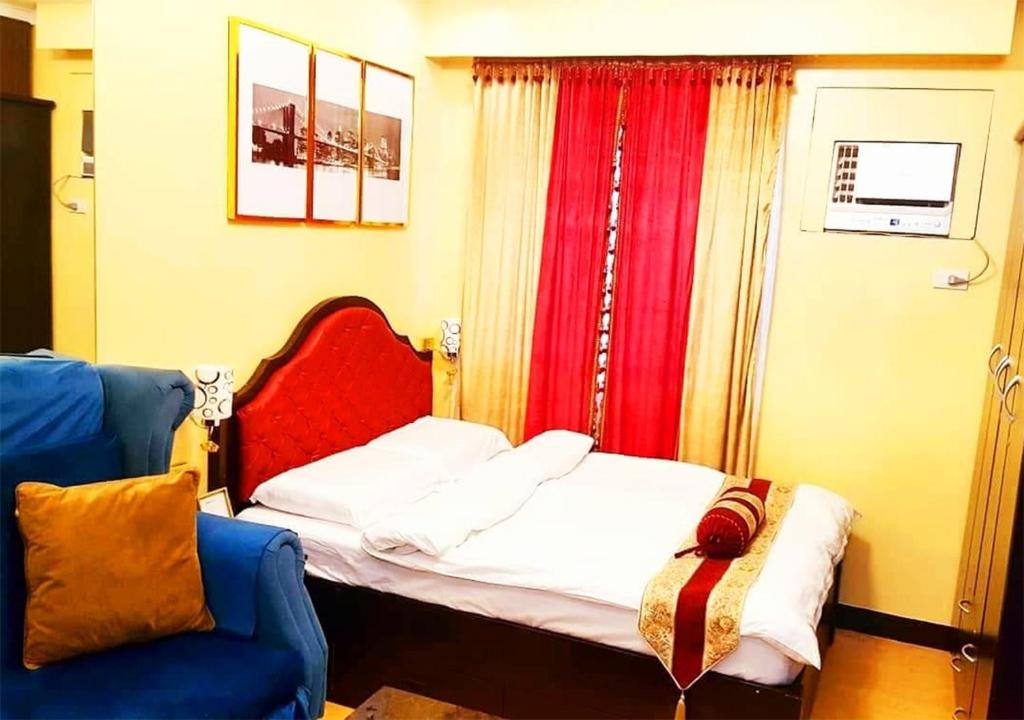 a bedroom with a bed and a blue chair at Trees Residences by Cail in Manila