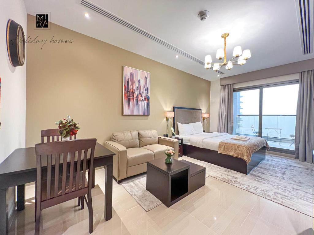 een slaapkamer en een woonkamer met een bed en een bank bij Mira Holiday Homes - Newly furnished studio in Downtown in Dubai
