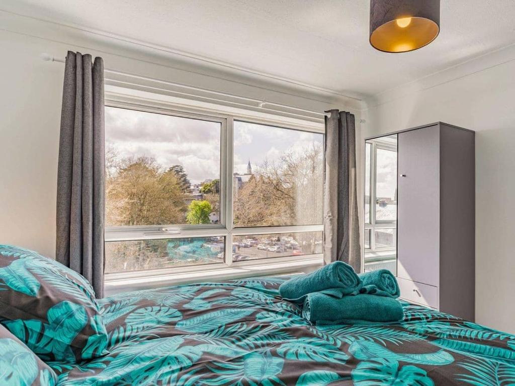 a bedroom with a bed and a large window at Lovely Magnolia Apartment 6 single beds in Torquay
