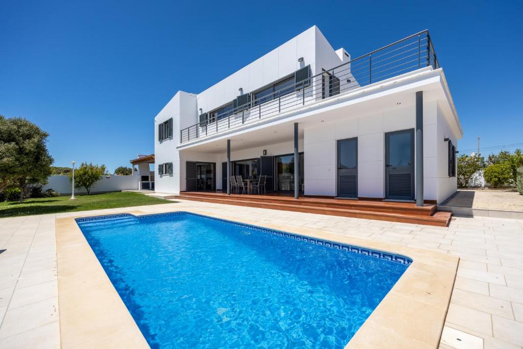 a villa with a swimming pool in front of a house at Pontalaia Village in Sagres
