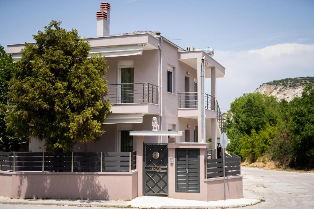 Una casa blanca con un árbol delante. en Onar Village Luxury Apartments, en Kavala