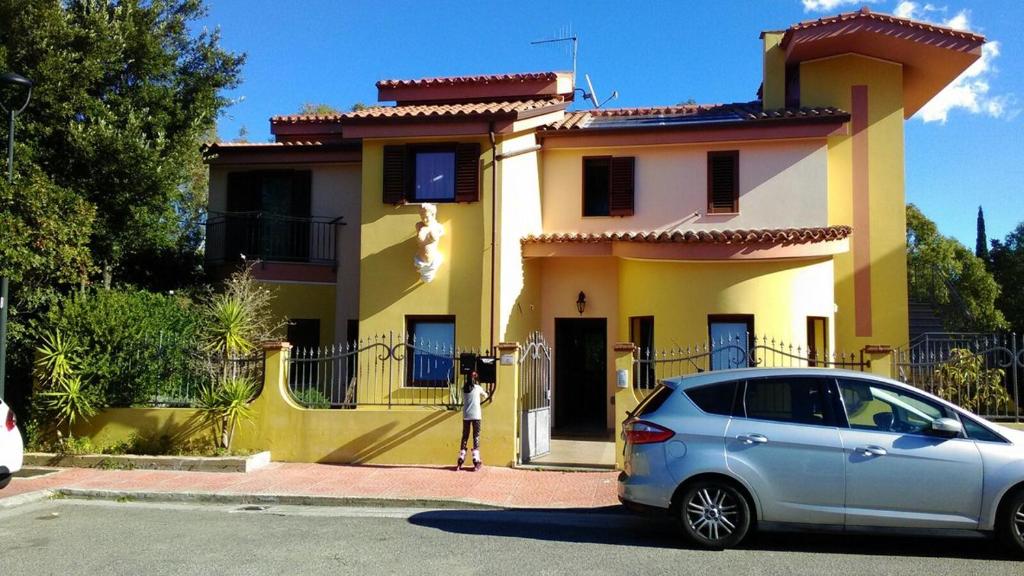 un coche plateado estacionado frente a una casa amarilla en Villa Magnolia, en Muravera