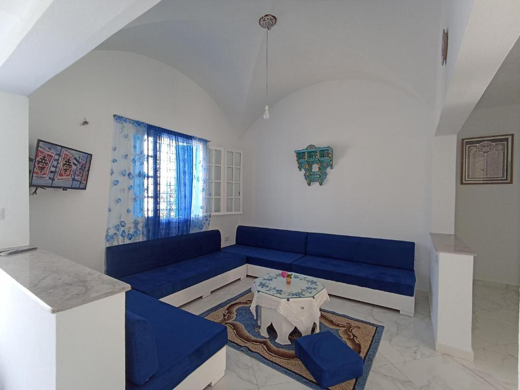 sala de estar con sofá azul y mesa en Maison S+1 très bien équipée à 2mn de la plage, en Kelibia