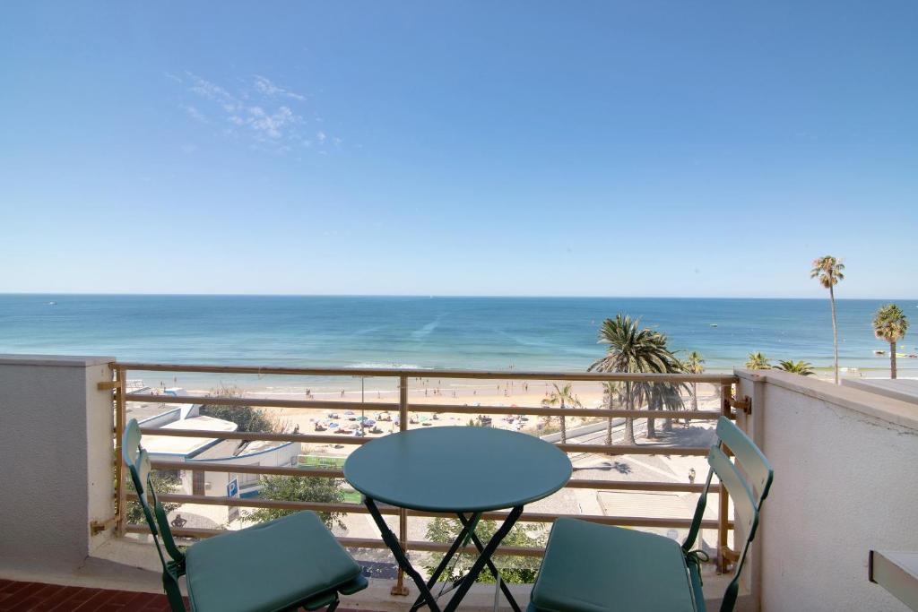 balcón con mesa y sillas y la playa en Ocean View Apartment en Armação de Pêra