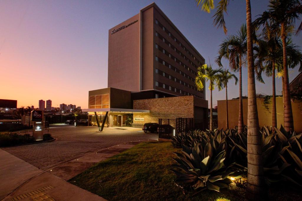 un grand bâtiment avec des palmiers devant lui dans l'établissement Rio Hotel By Bourbon Campinas, à Campinas