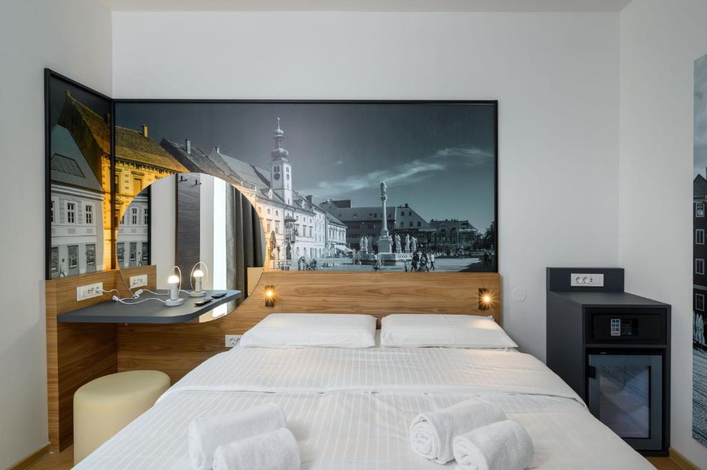 um quarto com uma grande cama branca e um mural de parede em B&B Hotel Maribor em Maribor