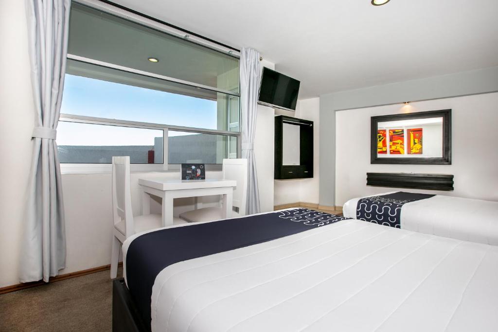 帕丘卡德索托的住宿－Hotel Euro Confort,Pachuca，一间卧室设有两张床、一张桌子和一个窗口。