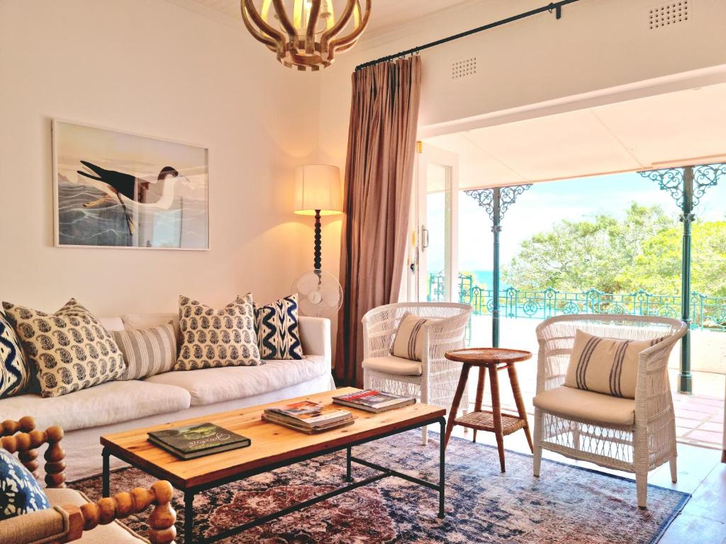 a living room with a couch and chairs and a table at Milkwood Cottage, Beachfront family vacation home, Sleeps 6 in Gordonʼs Bay