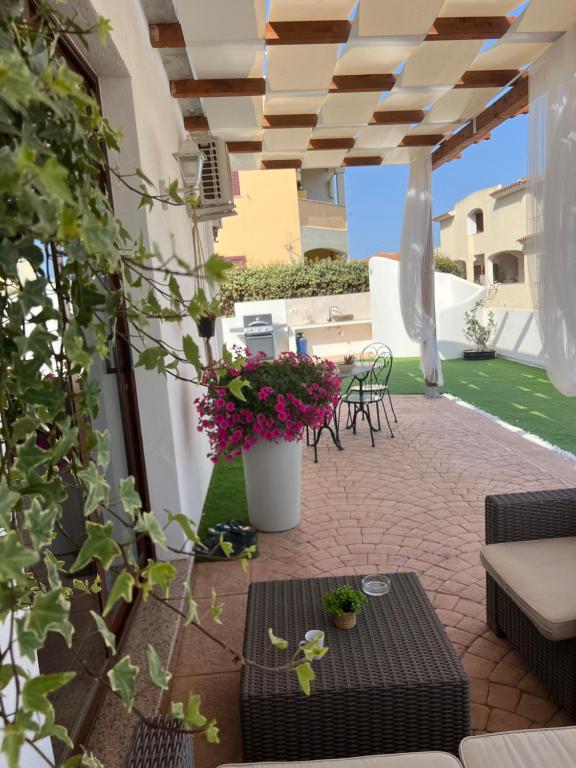 patio ze stołem, krzesłami i kwiatami w obiekcie Le residenze del mare Affittacamere w mieście La Caletta