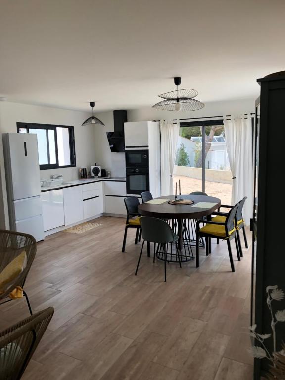 une cuisine et une salle à manger avec une table et des chaises dans l'établissement Maison neuve entre mer et forêt au calme, à Notre-Dame-de-Monts