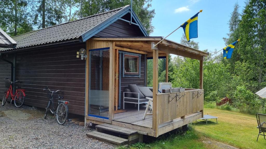 a wooden cabin with a deck and a bike at Fritidshus Rostockvägen 40B - Guest House - Bring own bed sheets in Norrtälje