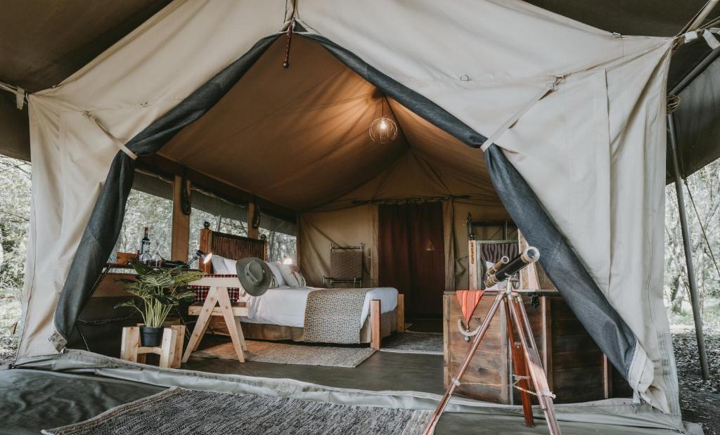 a tent with a bed and a table in it at Mara Olapa Camp in Masai Mara