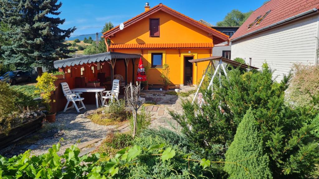 an orange house with a table in a garden at Domček u Babky in Liptovský Mikuláš