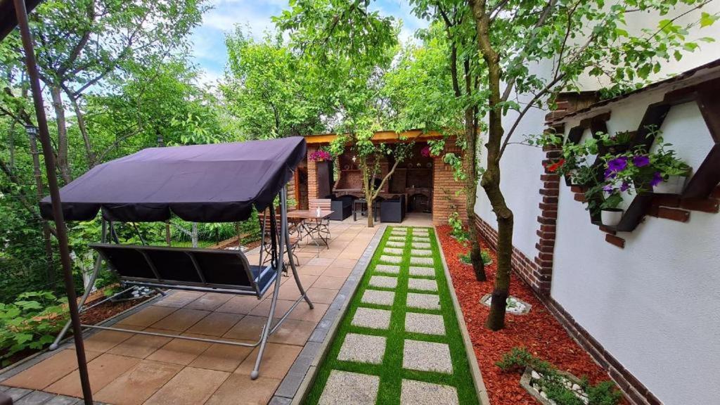 een patio met een zwarte parasol en bomen bij Cozy house with nice garden in heart of city center in Cluj-Napoca