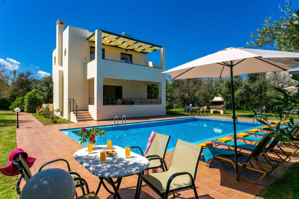 a villa with a swimming pool and a house at Villa Ilos by Villa Plus in Pírgos Psilonérou
