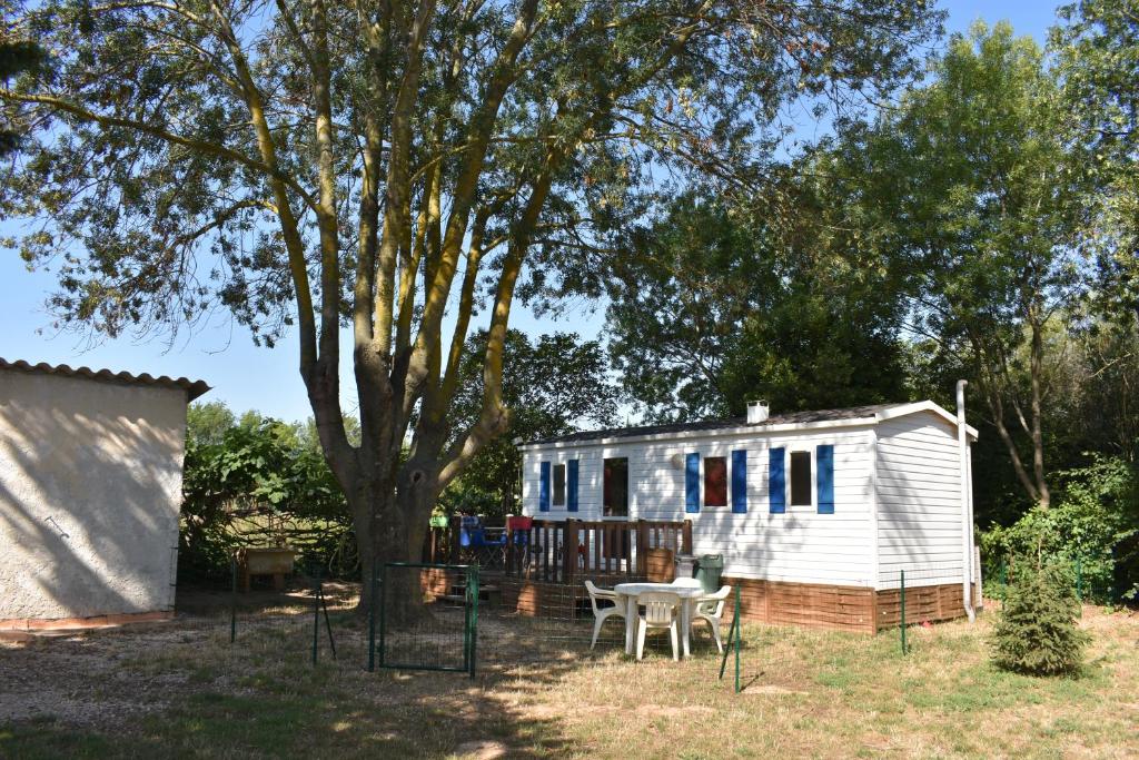 a tiny house with a table and a tree at mobil-home sur terrain bucolique in Hyères