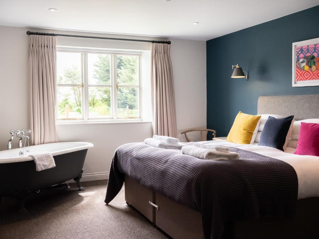 a bedroom with a bed and a tub and a window at The Stump in Cirencester