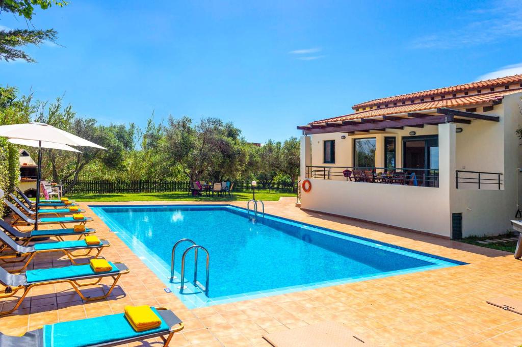 a swimming pool with lounge chairs and a house at Villa Anna Maria by Villa Plus in Pírgos Psilonérou