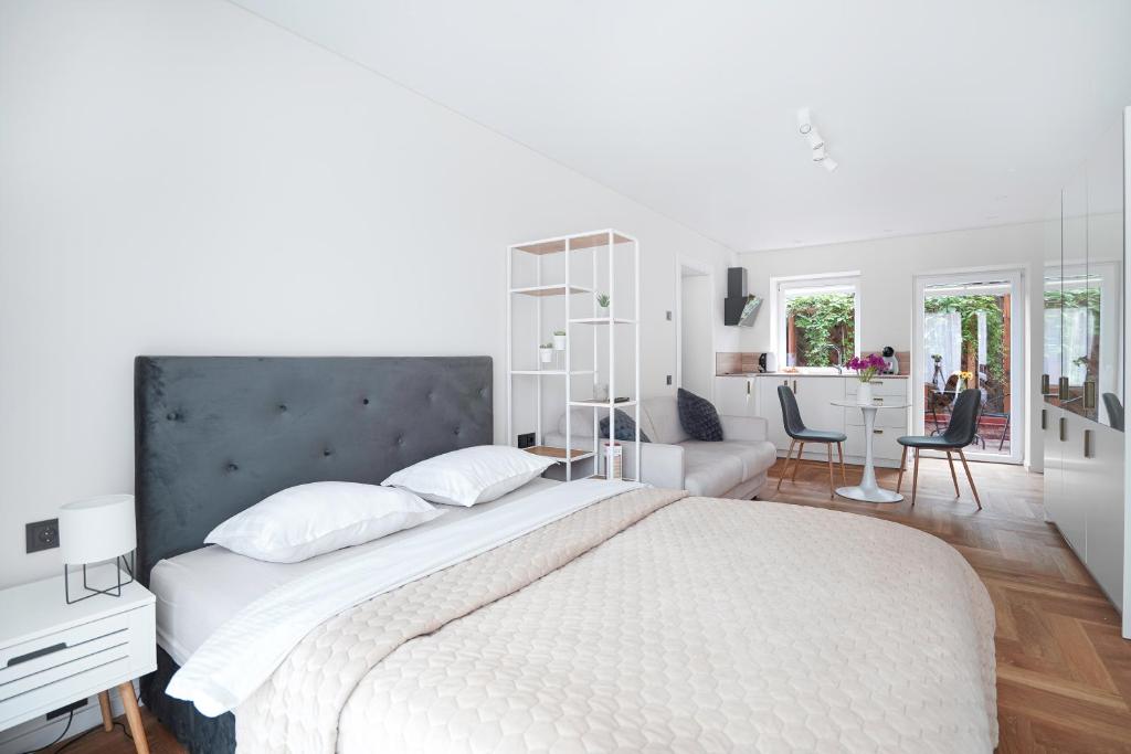 a white bedroom with a large bed and a living room at Exclusive OldNew apartments in city center in Panevėžys