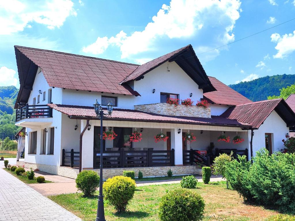 a white house with a red roof at Pensiunea Sub Horiță in Leordina