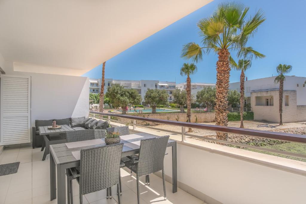 a balcony with a table and chairs and palm trees at Lucky Star Marina Apartment, with Pool in Lagos