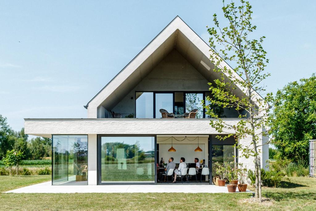 a house with a pitched roof with people sitting inside at Vakantiewoning Leie Lodge in Zulte