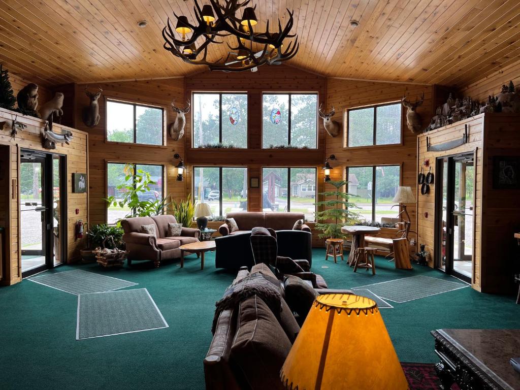 ein Wohnzimmer mit Sofas, Tischen und Fenstern in der Unterkunft Boulder Bear Motor Lodge in Boulder Junction