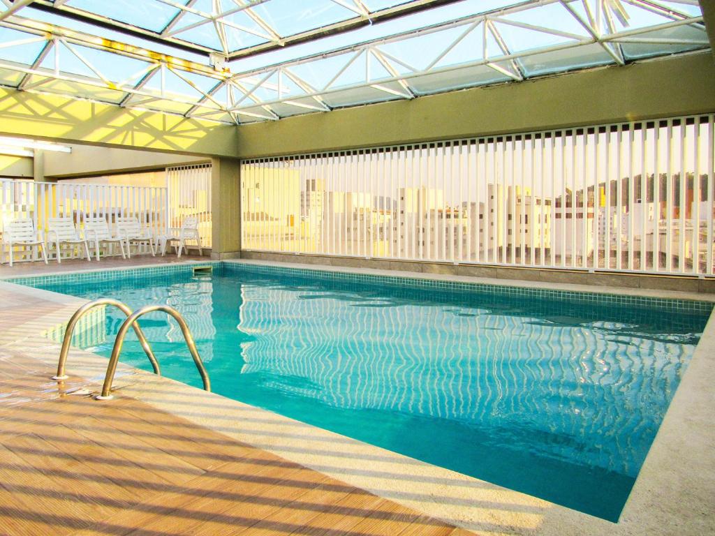 een groot zwembad in een gebouw met een stad bij Otimo Apto a 200m - Praia das Pitangueiras Guaruja in Guarujá