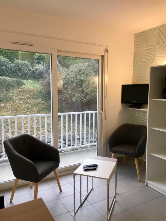 un salon avec deux chaises et une grande fenêtre dans l'établissement Joli petit studio au bord du lac, au Bourget-du-Lac